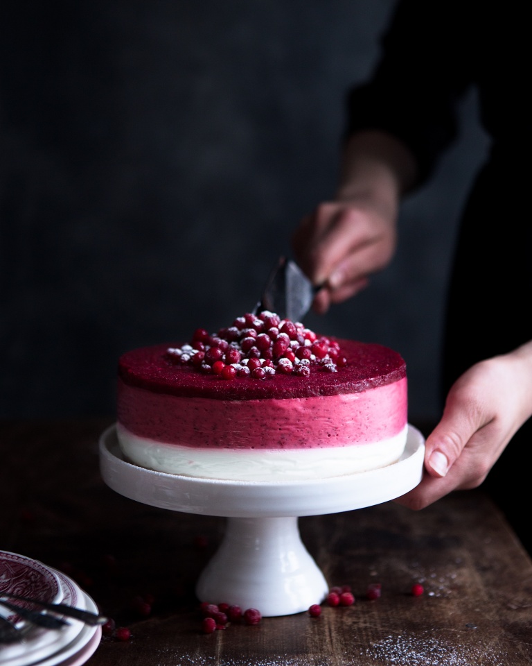 Cutting a layered lingonberry cheesecake